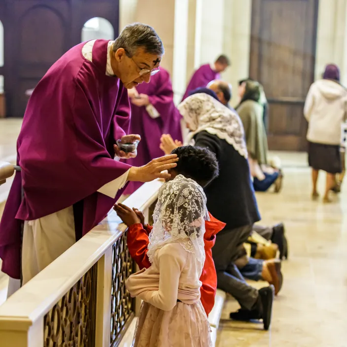 priest painting ash on person's forehead during ash wednesday