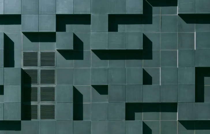 Dark teal wall with various cement blocks jutting outwards creating a horizontal and vertical pattern